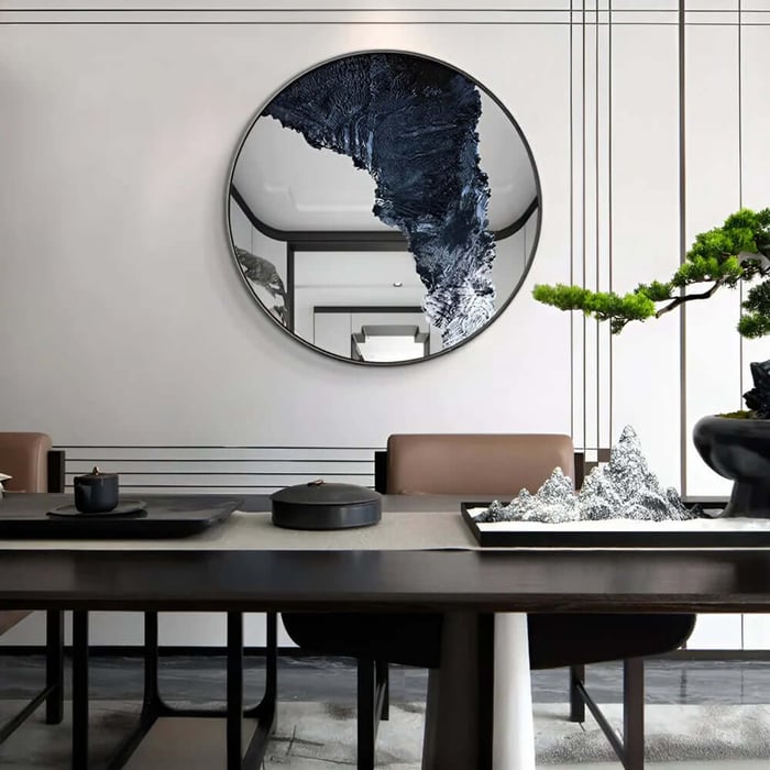 Round black-framed mirror with blue abstract design in minimalist dining room.