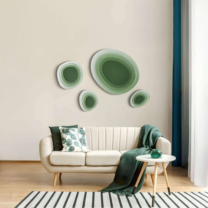 A modern living room with the Nuvora Green Gradient Cluster 3D Acrylic Wall Art featuring layered organic oval forms in soft green tones, displayed above a cream sofa with green cushions and minimal decor.