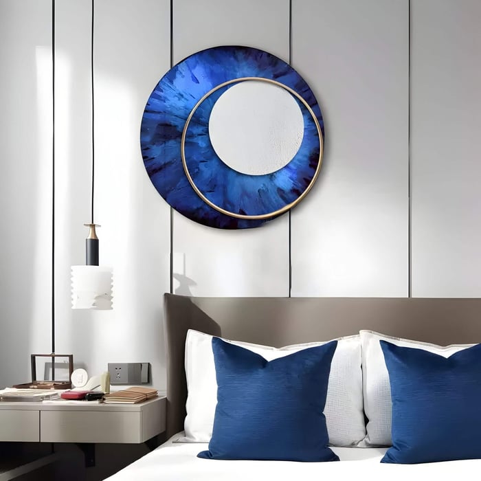 A modern bedroom interior featuring a round blue and gold iron wall art piece above the bed, with matching navy cushions and minimalist bedside decor, creating a cohesive and elegant look.