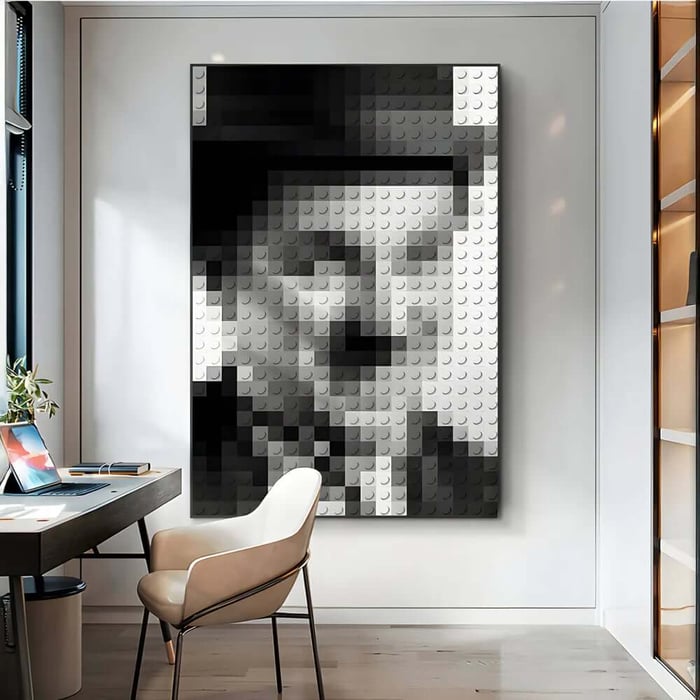 Modern home office with a desk and chair, featuring a large black-and-grey pixel-style portrait wall art with a textured block pattern on a white panelled wall.