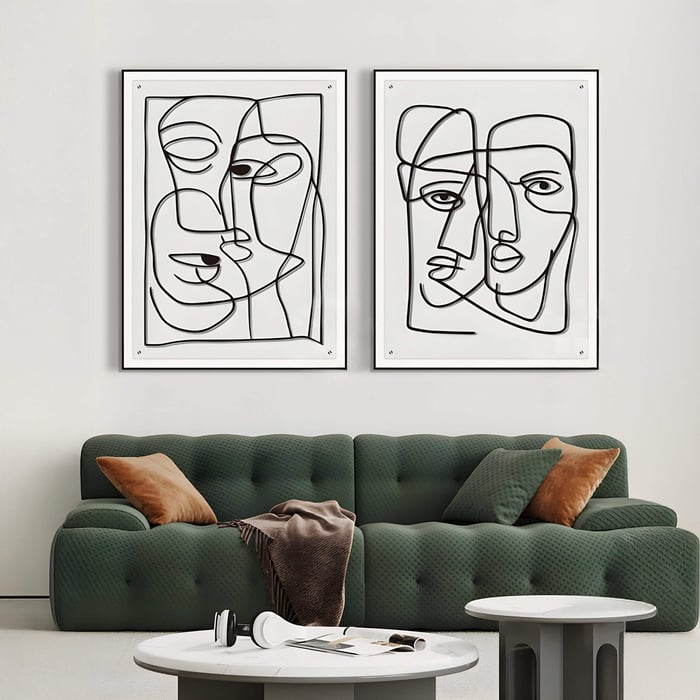 Set of 2 Minimalist black line face wall art drawings in a modern living room with a green sofa.