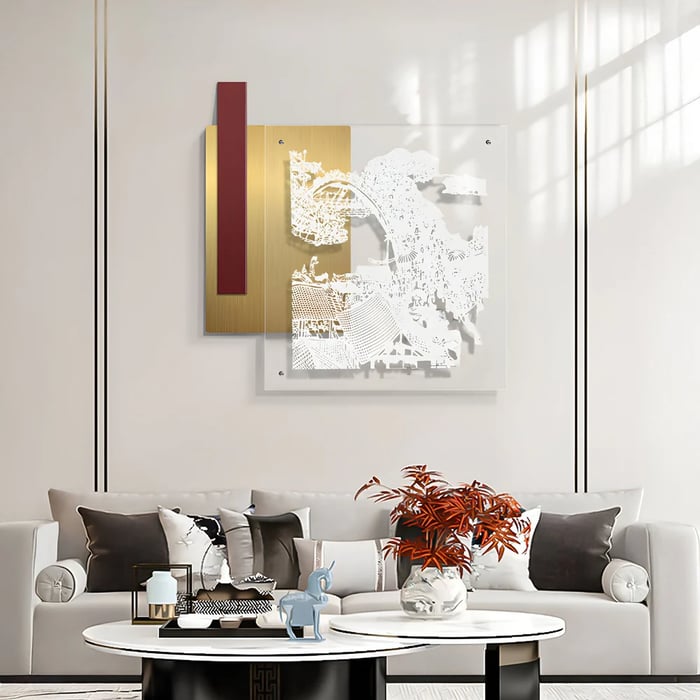 Neutral living room with a layered mixed-media architectural artwork in gold, white, and burgundy above a light sofa and round coffee tables.