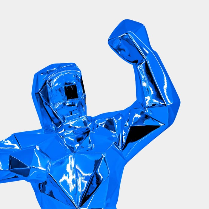 Vibrant blue geometric gorilla sculpture with a shiny, reflective finish, posed with raised fists against a plain white background.