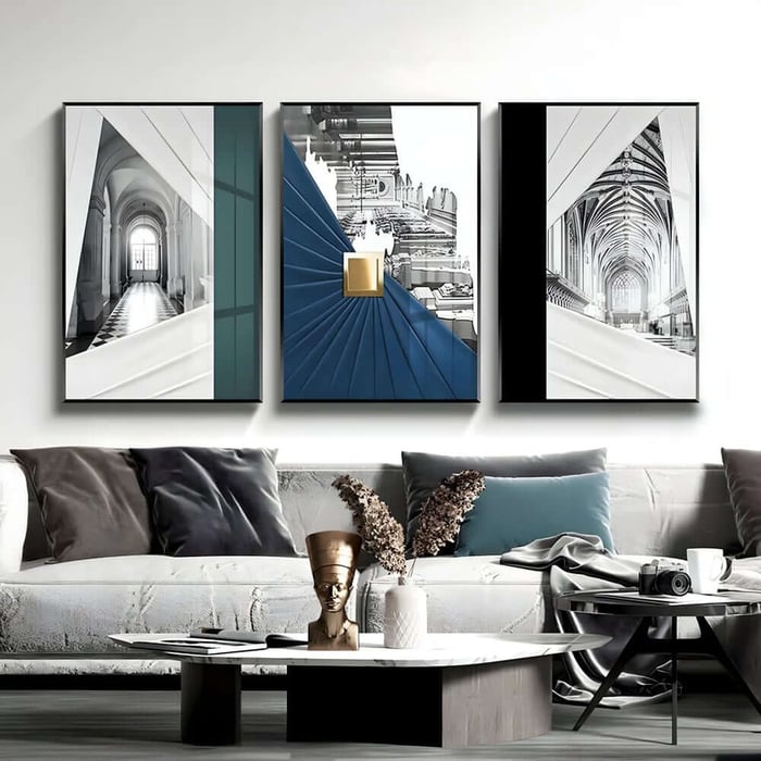 Three framed architectural prints above a sofa, featuring arches, vaulted ceilings and blue accents.