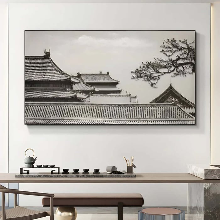 Wide framed photograph of traditional Japanese rooftops with a pine branch against a pale sky.