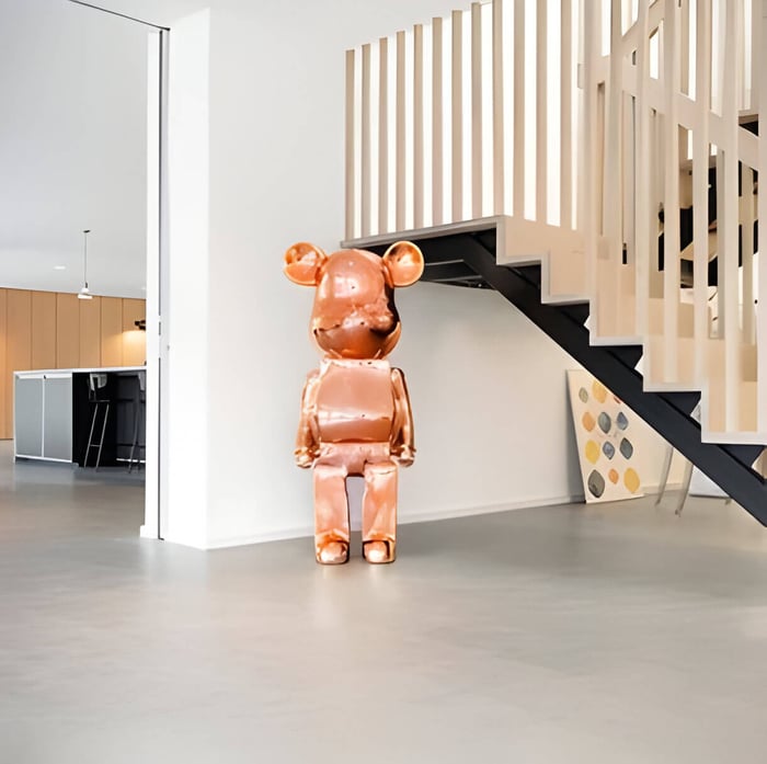 a rose gold giant bear sculpture at the bottom of the stairs in a house