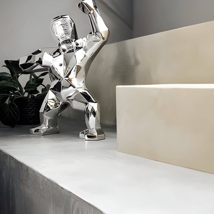 A chrome gorilla sculpture on modern shelf