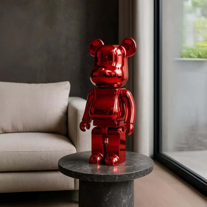 Glossy red bear sculpture on a round marble side table in a contemporary living room.