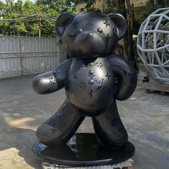 Oversized matte black bear sculpture with subtle monogram pattern standing on a plinth outdoors.