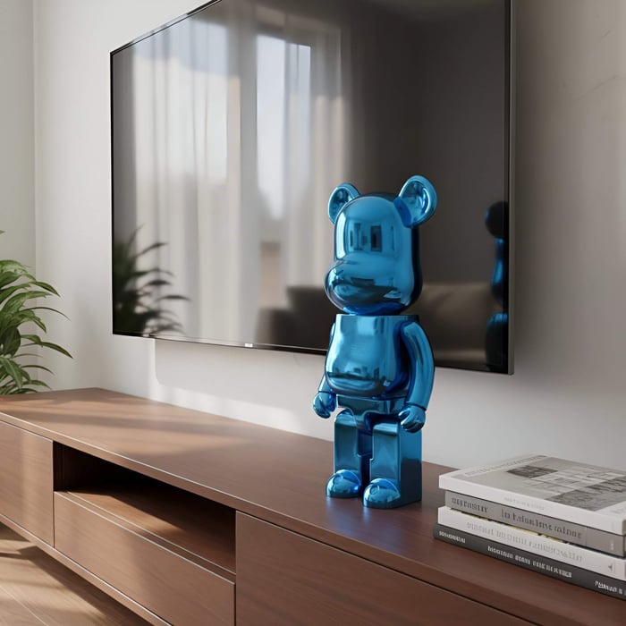 A glossy blue bear-shaped sculpture displayed on a wooden TV console beside a flat-screen television in a bright modern living room.
