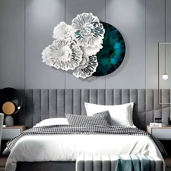 Stylish grey bedroom with a tall tufted headboard, white bedding and houndstooth cushions, featuring a large circular teal artwork layered with white floral metal wall sculptures above the bed.