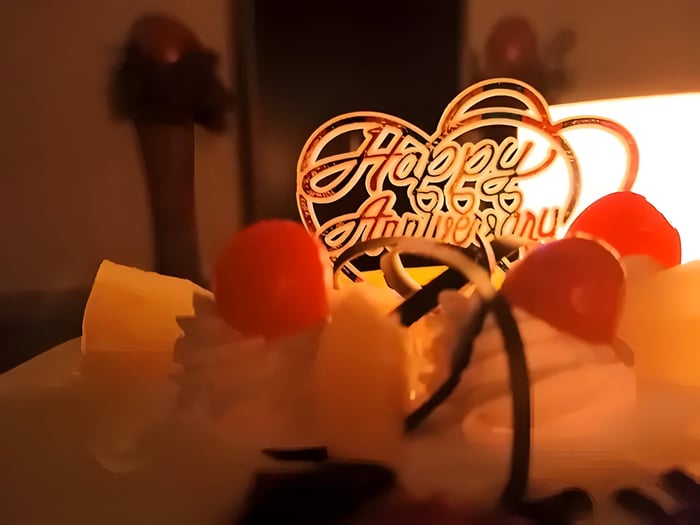 A happy anniversary cake topper next to cherries