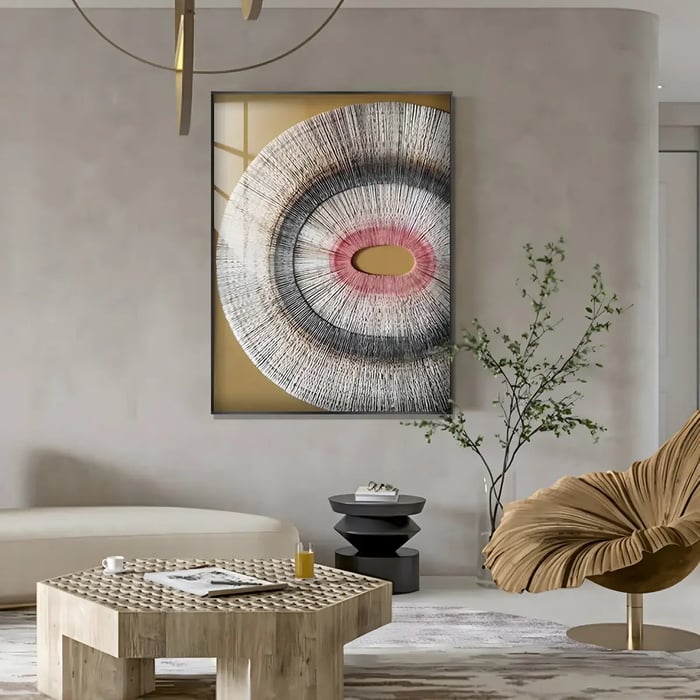 A refined living space with a large framed artwork featuring a radial textured design in gray, pink, and gold tones, adding a focal point to the minimalist decor.