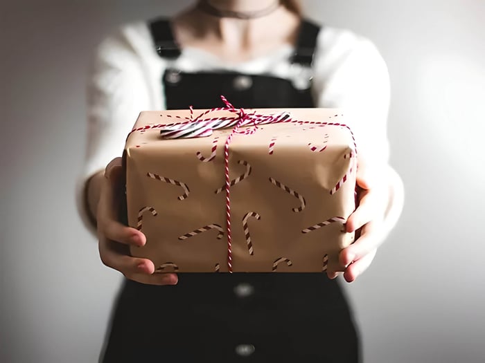 a gift wrapped in brown wrapping paper with candy canes on, and red ribbon.