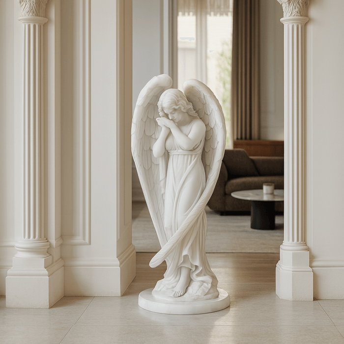 White marble angel sculpture with folded wings and serene pose displayed in an elegant indoor setting.
