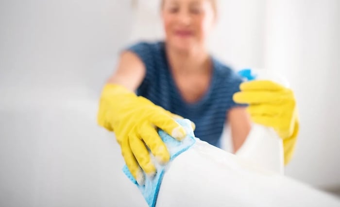a lady cleaning using spray bottle and cloth