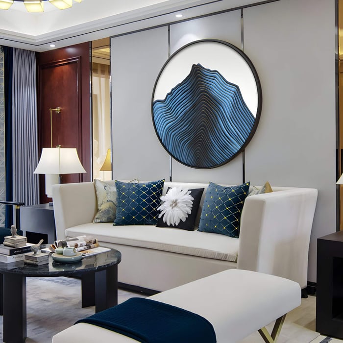 A round zen art piece with a topographic ripple pattern in shades of black and deep blue adds texture and visual intrigue to this elegant living room, where dining room art meets architectural sculpture.