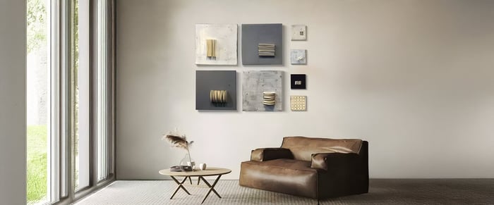 Minimalist room with leather armchair and mixed-media grid art featuring layered textures and neutral tones.