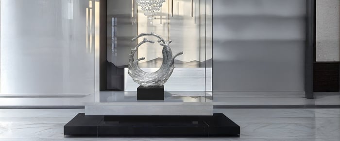 Modern glass-encased sculpture of a circular wave on a pedestal.