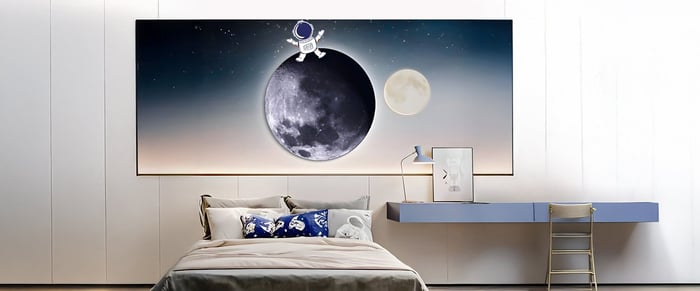 Space-themed bedroom with astronaut and moon wall art above bed and a sleek modern desk setup.