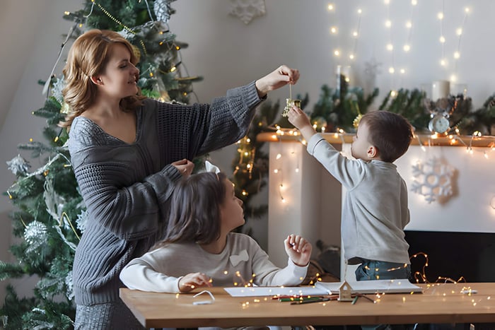 a woman and 2 children decorating for Christmas