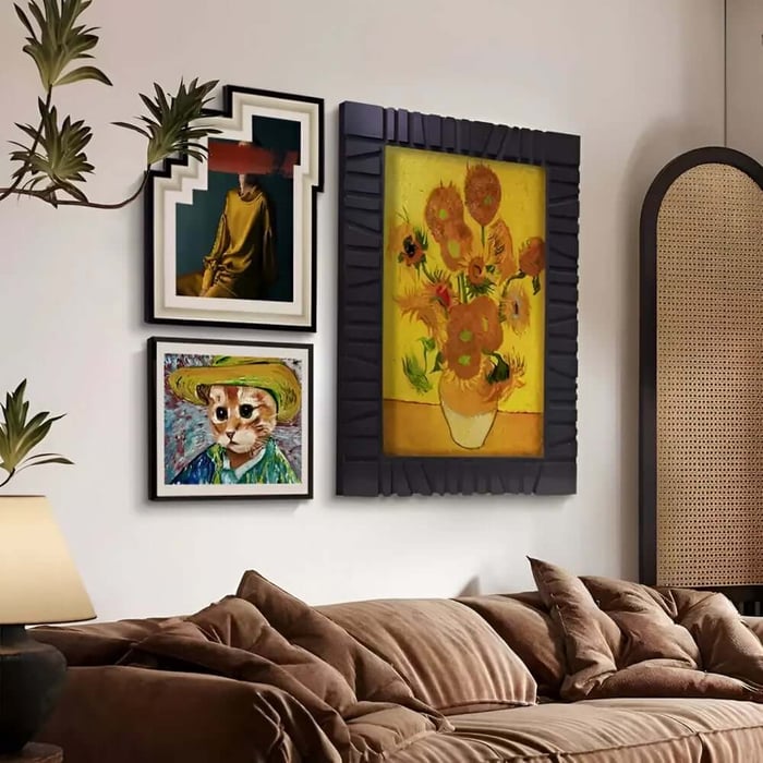 Warm bedroom scene with rumpled brown bedding and a mixed gallery wall, featuring a large sunflower still life and smaller fashion/animal art prints.