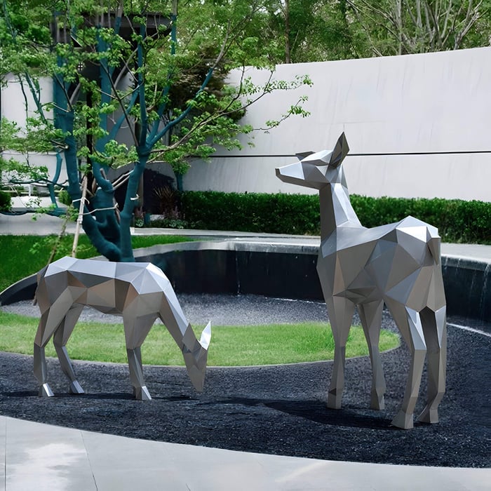 Two polygonal metallic deer sculptures in a landscaped garden.