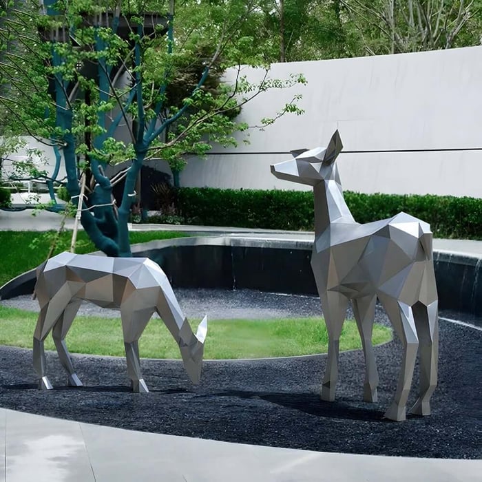 Two geometric stainless steel deer sculptures in a modern courtyard garden beside a curved water feature.