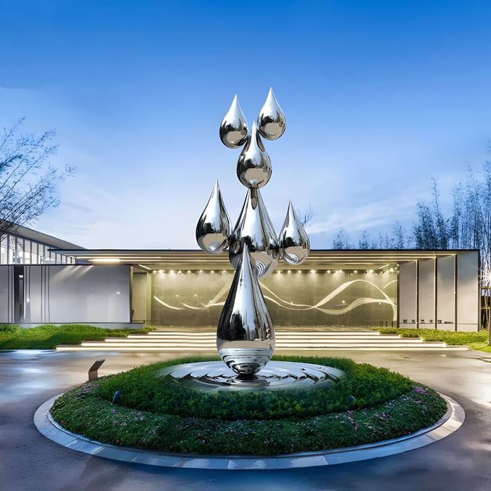Futuristic chrome water droplet sculpture in front of a modern building.