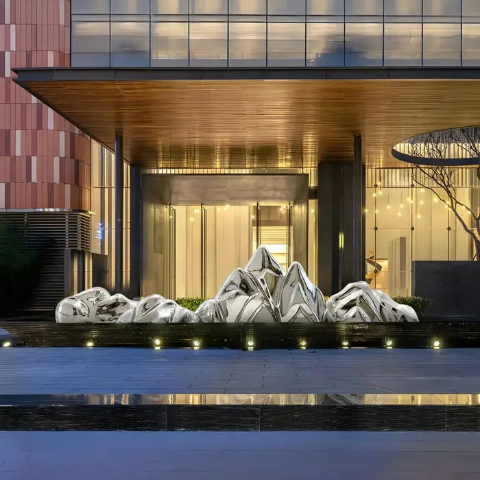 "A sleek, abstract metallic sculpture in a modern outdoor setting, featuring reflective surfaces under ambient lighting.