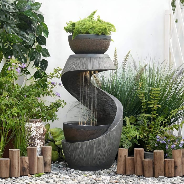 A modern functional garden sculpture featuring a tiered spiral water fountain with cascading streams and lush greenery, blending art and utility in an outdoor setting.