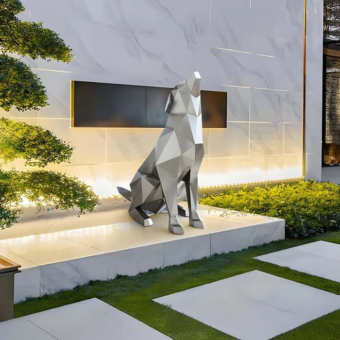 Faceted metal wolf geometric sculpture on a raised outdoor platform beside a modern wall.