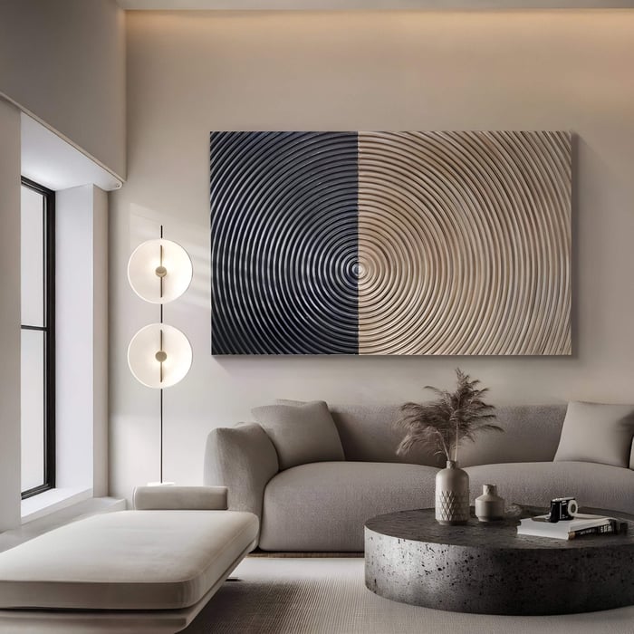 A modern living room features a light grey sofa, matching ottoman, round coffee table, and tall floor lamp. Above the sofa hangs Giant Sculptures Artura Beige & Black Hand-Painted 3D Relief Wall Art, enhancing the calm Wabi-Sabi-inspired decor.