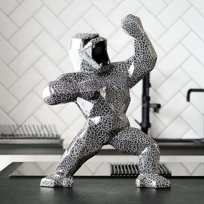 Black and white crackle-pattern gorilla sculpture standing on a sleek kitchen counter.