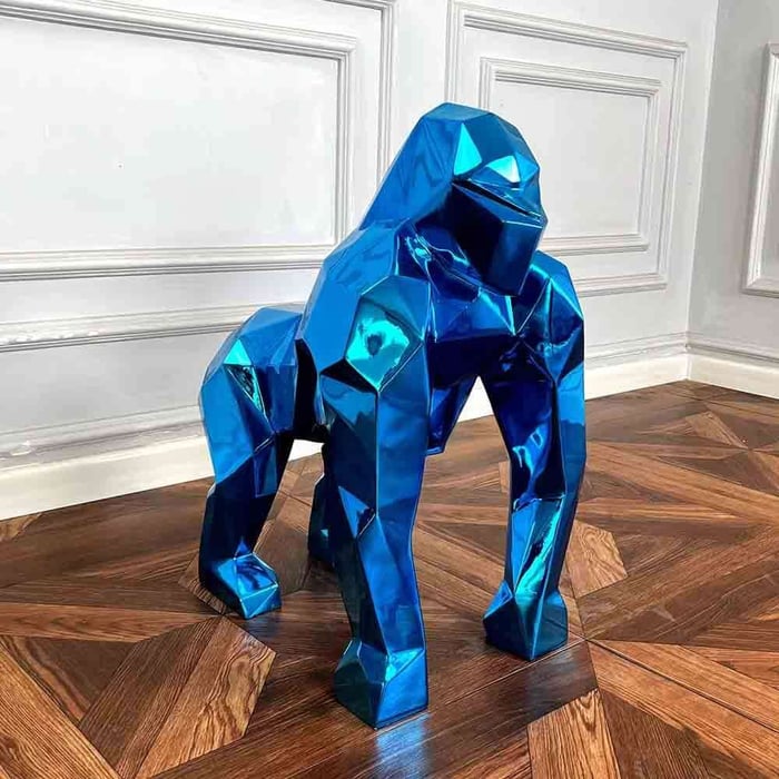 Large metallic blue gorilla sculpture standing on polished wooden parquet floor.