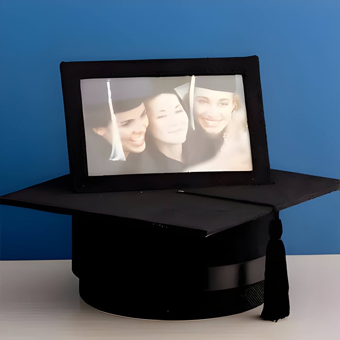 A black graduation hat memory box with a photo of 3 graduates ontop