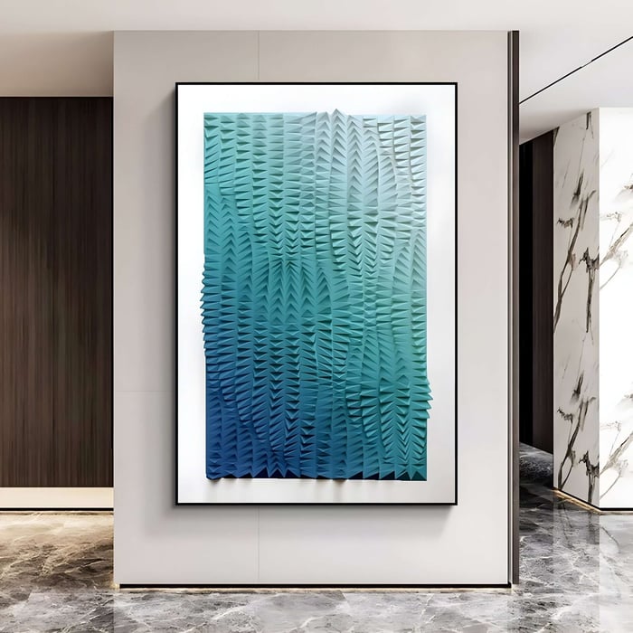 A modern interior features the Elytrum Blue Gradient Hand-Painted 3D Wood Relief Art by Giant Sculptures. Its textured abstract design in blue and green captivates on a white wall, harmonized with marble and wood paneling, and beautifully contrasted against the reflective gray marble floor.