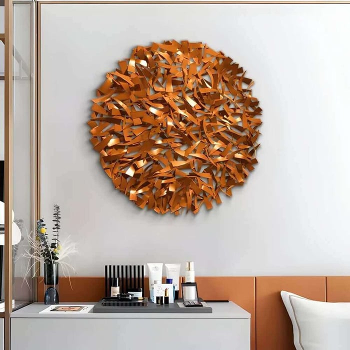 Round abstract iron wall sculpture in warm gold tones above a minimalist console table.