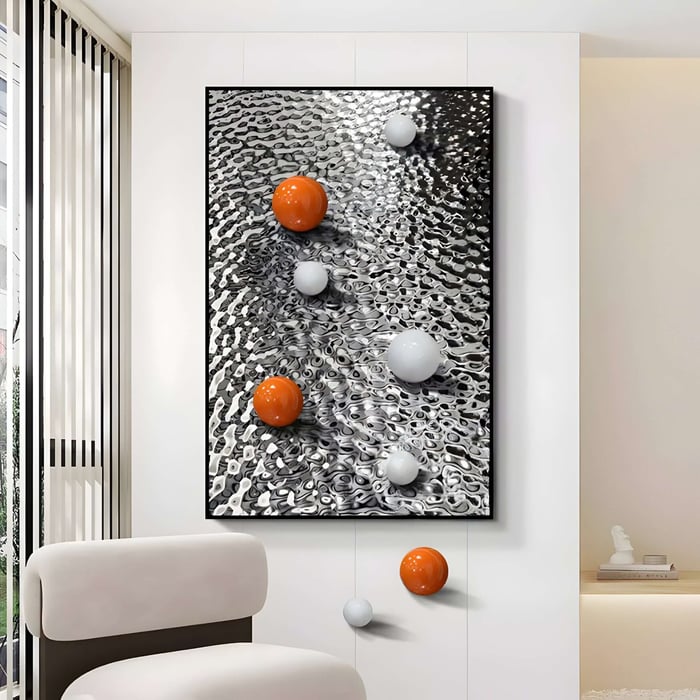 In a contemporary office room, Giant Sculptures Luminosa Orange & White Orb Textured Metal 3D Art, with its black and white wavy background and orange spheres, effortlessly enhances the space alongside a chair in the foreground.