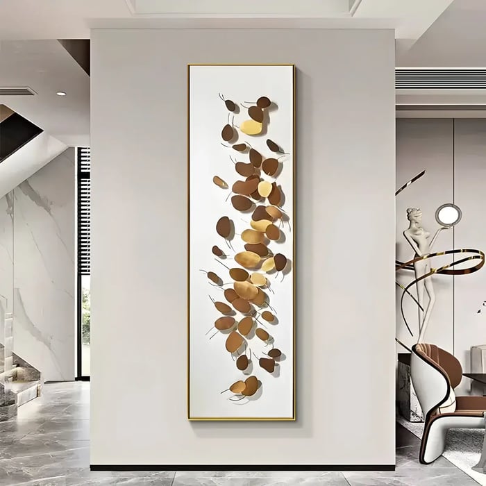 A luxurious interior featuring a tall framed artwork with metallic gold and bronze leaves, creating a dynamic and textured focal point.