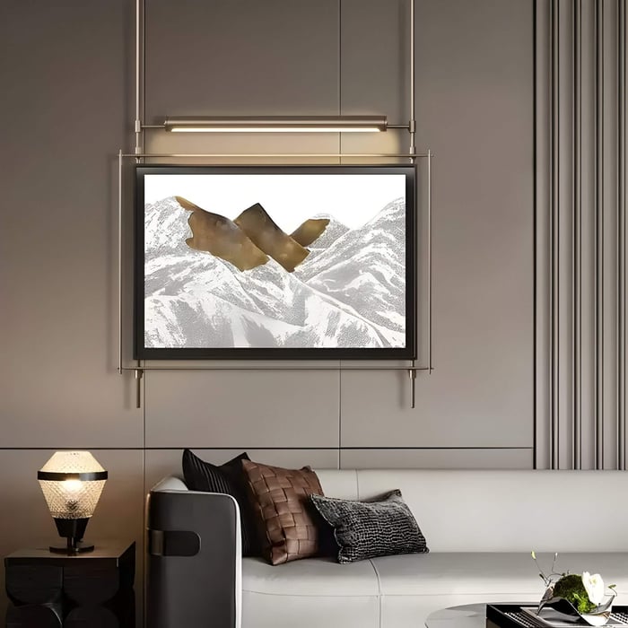 Modern living room with mountain-themed wall art featuring abstract bronze accents, framed above a sleek white and black sofa.