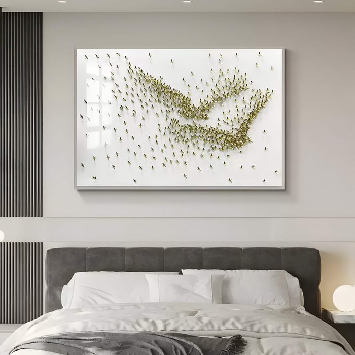 Luxury modern bedroom with a grey upholstered bed and white linens, featuring a large white-framed sculptural wall art panel of hundreds of metallic gold bird‑shaped accents arranged in sweeping patterns above the headboard.
