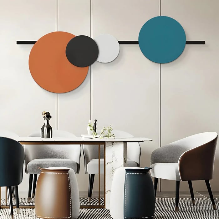 A stylish dining area featuring an abstract arrangement of large, overlapping circular panels in burnt orange, deep blue, black, and white, mounted on a sleek wall.