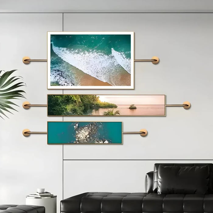 A sleek interior featuring a unique triptych wall art arrangement depicting serene ocean and nature scenes, mounted with gold brackets against a neutral background.