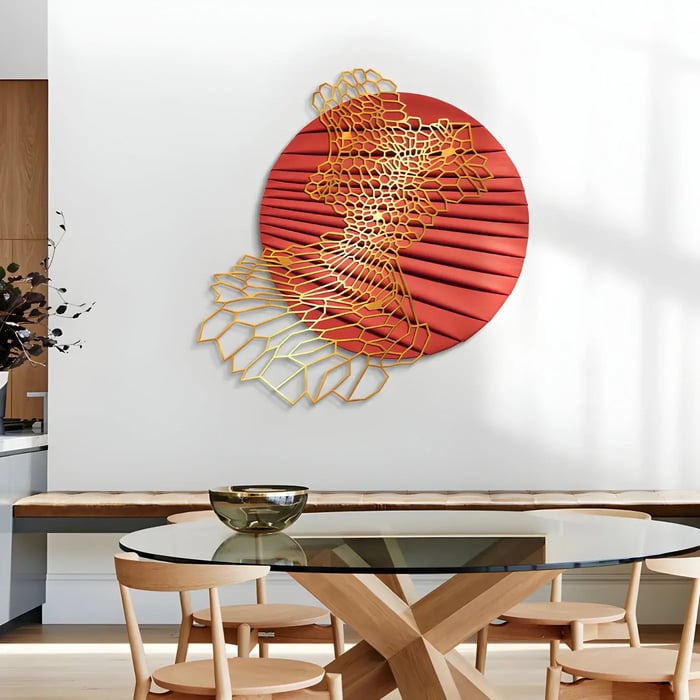 Red and gold abstract wall art in dining area – A striking circular red and gold metal wall sculpture mounted above a dining bench in a contemporary setting.