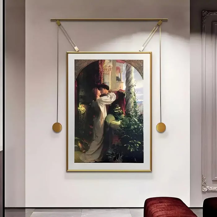 A framed reproduction of a romantic classical painting depicting a couple embracing, displayed with a unique gold hanging frame system in an upscale setting.