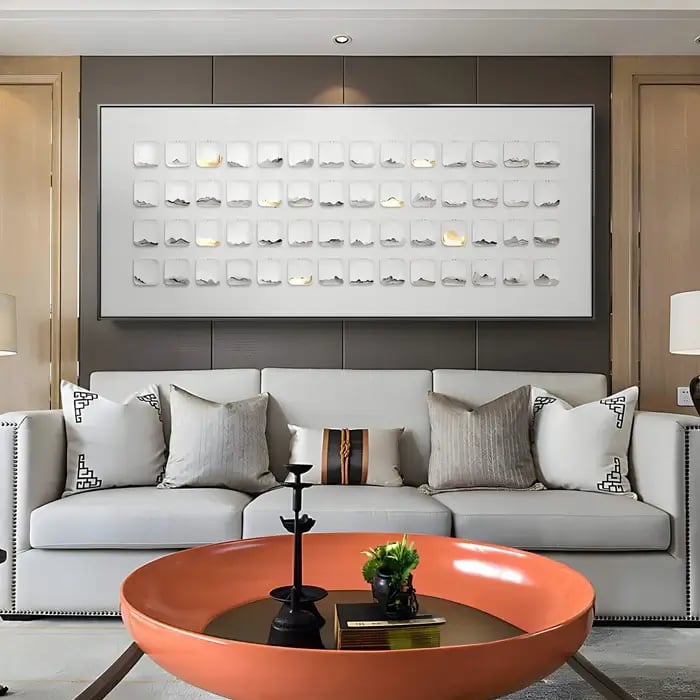 A neutral-toned sofa setting with a long, rectangular wall art piece featuring a grid of raised elements, adding depth and texture.