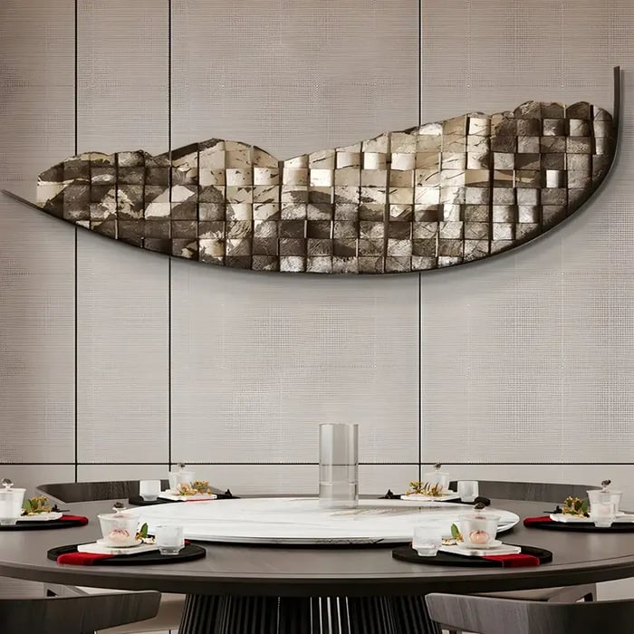 A sophisticated dining area with a curved metallic mosaic wall sculpture in gold and silver tones above a round dining table set with modern tableware.