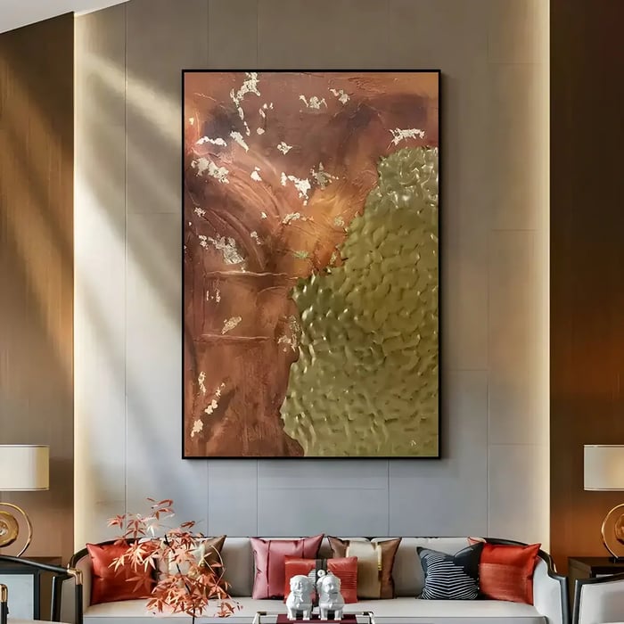 A large abstract painting featuring earthy tones with hints of gold leaf, creating a dramatic effect above a sophisticated sofa in a luxurious living room.
