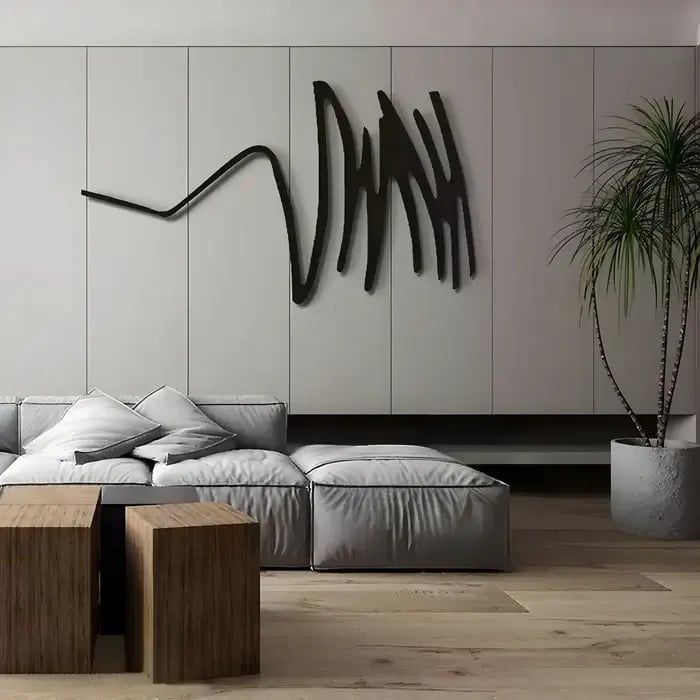  A minimalist modern living room with a black abstract wall sculpture, mounted above a plush grey sectional and wooden accent tables.